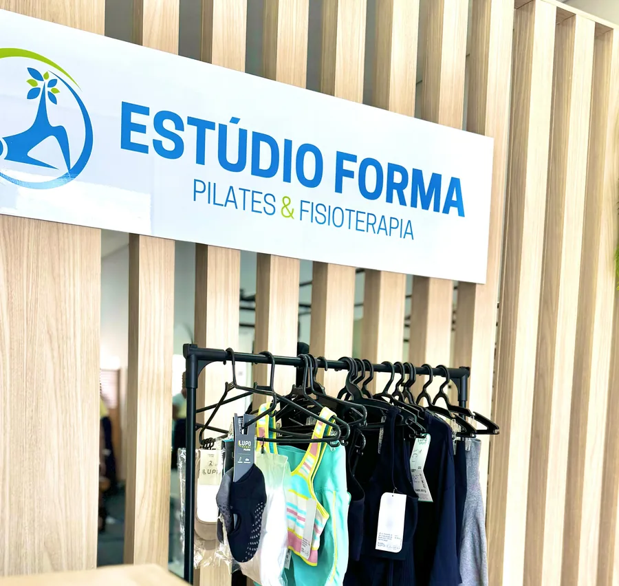 Placa Estúdio Forma Pilates e Fisioterapia sobre o ripado de madeira da recepção